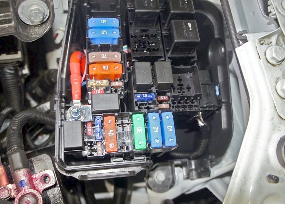 Photographie du compartiment moteur, montrant la disposition des composants et fusibles.